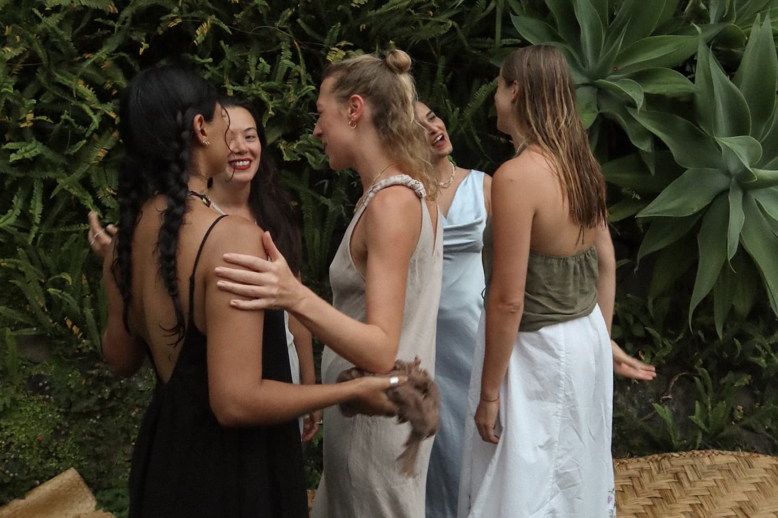 Women laughing together in a garden, one with an arm around another