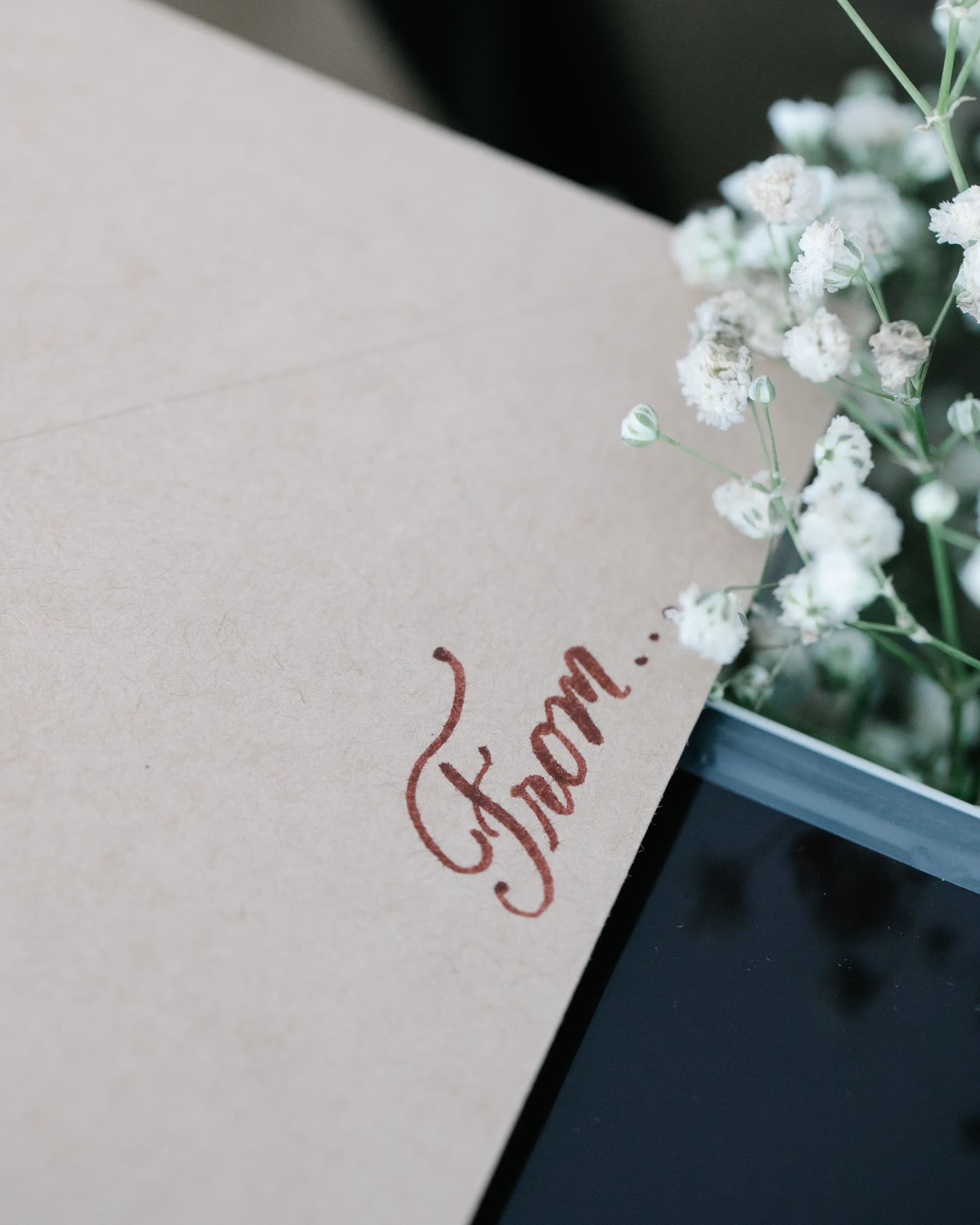 A kraft envelope inscribed 'From' in brown calligraphy, white gypsophila beside it